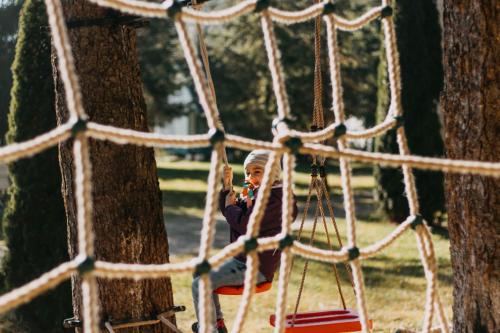 a little girl riding on a swing in a park at Tusnad Camping in Băile Tuşnad