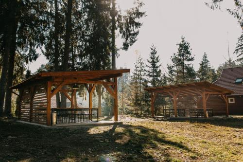 two wooden pavilions in a park with trees at Tusnad Camping in Băile Tuşnad