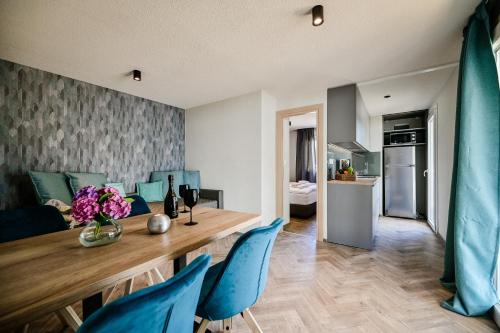 a kitchen and living room with a wooden table and blue chairs at Mobile Homes Krk Silo in Šilo