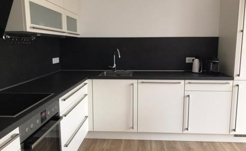 a kitchen with white cabinets and a black counter top at Villa am Wall in Osnabrück
