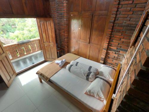 a bed in a room with a brick wall at Wisma Pancoeran in Grigak