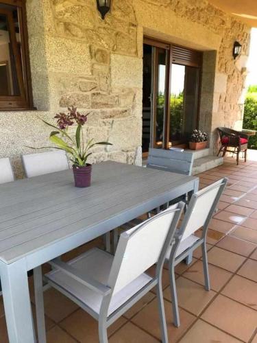 a wooden table and chairs with a potted plant on a patio at Cubelas Porto do Son in Porto do Son