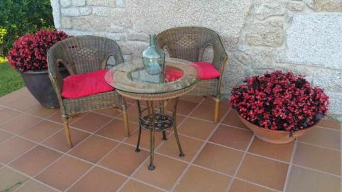 two wicker chairs and a table with a vase on it at Cubelas Porto do Son in Porto do Son