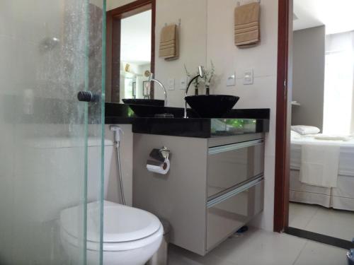a bathroom with a toilet and a sink and a mirror at Bangalô no alto da colina no Villas do Pratagy - Maceió in Maceió