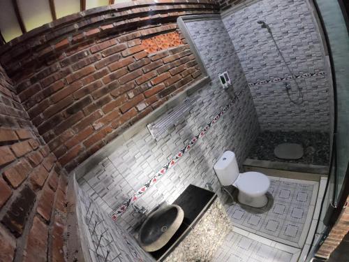 a brick bathroom with a sink and a toilet at Wisma Pancoeran in Grigak