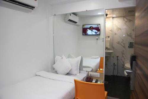 Habitación pequeña con cama y TV en la pared. en Hotel Lucky Galaxy en Bombay