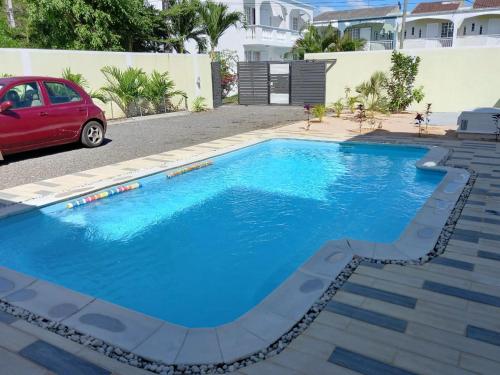 una piscina con un coche rojo estacionado al lado en Idyllic Villa in Pereybere with Private Pool, en Pereybere
