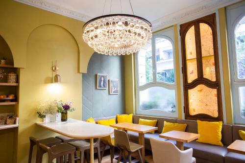 une salle à manger avec des chaises jaunes et un lustre dans l'établissement Hotel Louison, à Paris