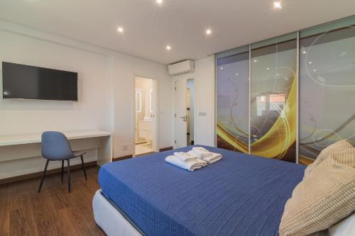 una camera con letto blu, scrivania e TV di Vilamoura Premium Apartment by Homing a Vilamoura