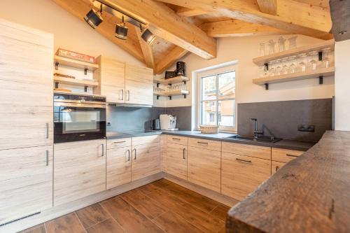 a kitchen with wooden cabinets and a large window at Tauernlodges Uttendorf by ALPS RESORTS in Uttendorf