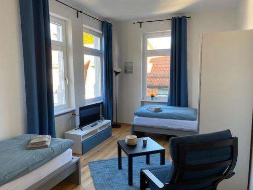 ein Wohnzimmer mit einem Bett, einem Stuhl und einem TV in der Unterkunft Gästehaus Windheim Ettlingen Stadt in Ettlingen