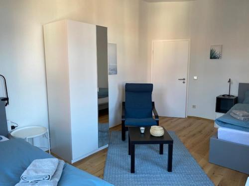 a living room with a bed and a blue chair at Gästehaus Windheim Ettlingen Stadt in Ettlingen
