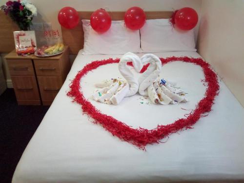 two white swans forming a heart on a bed at Britannia Inn Hotel in Ilford