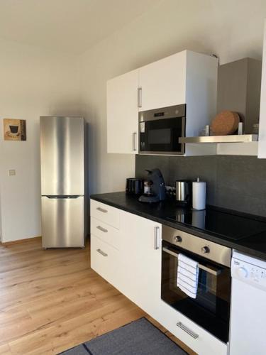a kitchen with white cabinets and a stainless steel refrigerator at Gästehaus Windheim Ettlingen Stadt in Ettlingen