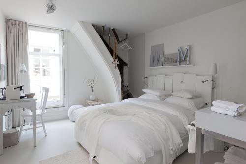 a white bedroom with a white bed and a window at Mother Goose Hotel in Utrecht