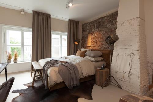 a bedroom with a bed and a brick wall at Mother Goose Hotel in Utrecht