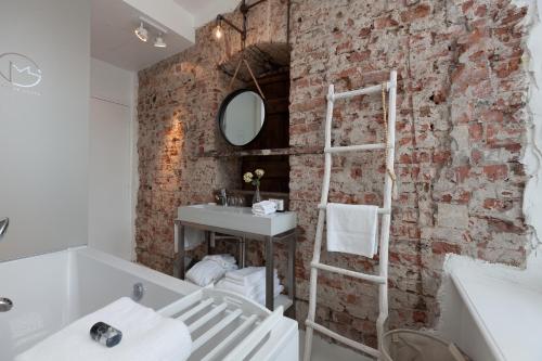 a brick wall in a bathroom with a sink and a mirror at Mother Goose Hotel in Utrecht