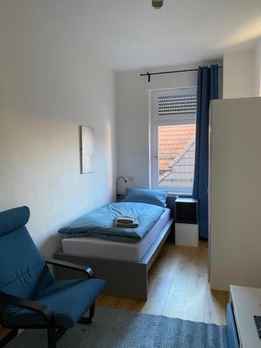 a bedroom with a bed and a chair and a window at Gästehaus Windheim Ettlingen Stadt in Ettlingen