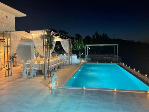 a swimming pool at night with a table and a dining area at Eva Villas West and East with 2 private infinity pool & and panoramic sea view in Gerani