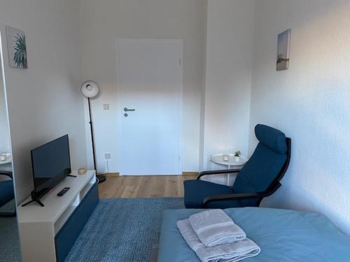 a room with a bed and a tv and a chair at Gästehaus Windheim Ettlingen Stadt in Ettlingen