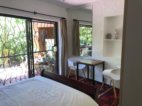 1 dormitorio con cama, mesa y balcón en Fig Tree Cottage Close to Sea and Shops en Hout Bay