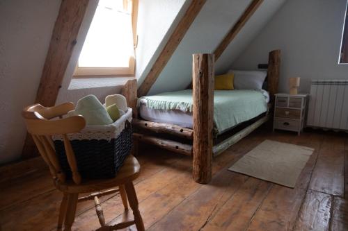 a attic bedroom with a bed and a chair at Kuća za odmor Mećava in Mrkopalj