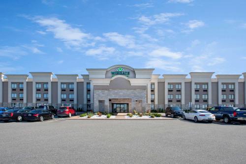 a large building with cars parked in a parking lot at Wingate by Wyndham Detroit Metro Airport in Romulus