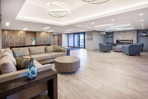 a lobby with couches and a table and a piano at Wingate by Wyndham Detroit Metro Airport in Romulus