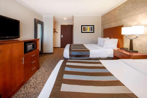 a hotel room with two beds and a flat screen tv at Wingate by Wyndham Detroit Metro Airport in Romulus