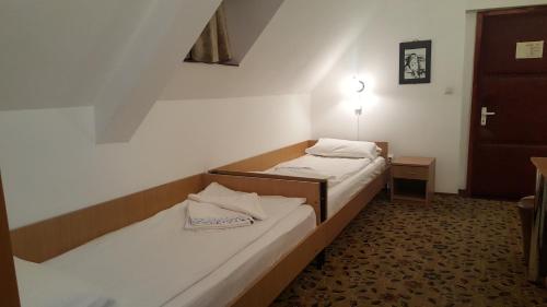 two beds in a small room with a door at Pensiunea Podul Minciunilor in Sibiu