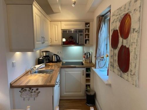 a small kitchen with white cabinets and a sink at Deichhof Whg 8 in Dunsum