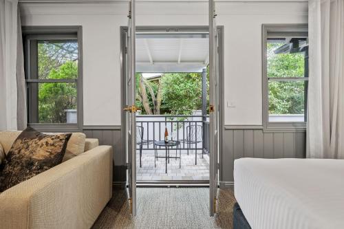 a bedroom with a bed and a couch and a balcony at Wildes Hotel Kangaroo Valley in Kangaroo Valley
