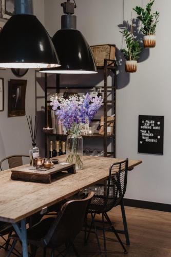 a dining room table with a vase of purple flowers at Mother Goose Hotel in Utrecht