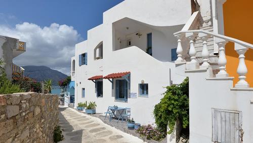 a white building with a table on a street at Maistrali Studios in Diafani