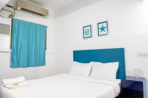 - une chambre avec un grand lit et un rideau bleu dans l'établissement Deer Suites and Spa- Rock Beach White Town Zone , French Quarter, Pondicherry, à Pondichéry