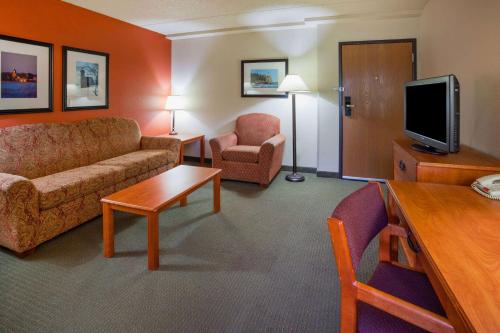 a hotel room with a couch and a chair and a tv at AmericInn by Wyndham Wetmore Munising in Wetmore