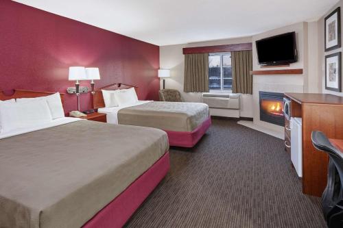 a hotel room with two beds and a television at AmericInn by Wyndham Douglas/Saugatuck in Saugatuck