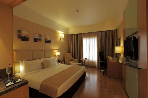 a hotel room with a bed and a television at Mysore County Retreat in Mysore