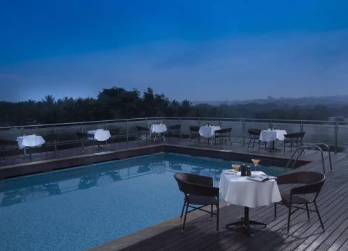 una piscina con mesas y sillas en una terraza en Mysore County Retreat, en Mysore