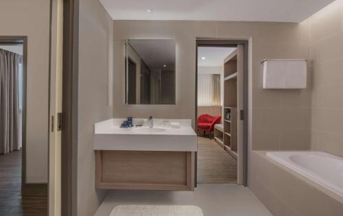 a bathroom with a sink and a tub and a mirror at Park Inn by Radisson North Edsa in Manila