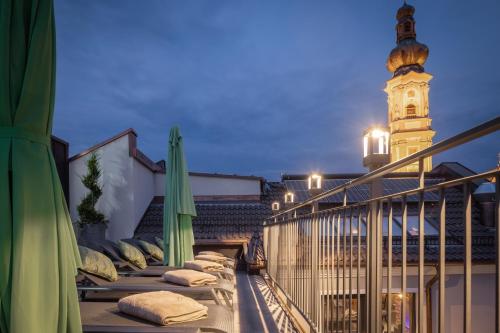 a balcony with pillows and a clock tower in the background at Hotel-Gasthof Höttl in Deggendorf