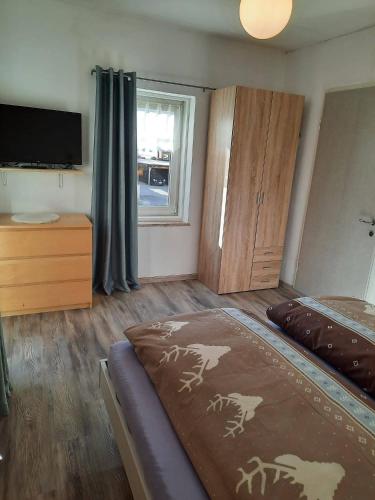 a bedroom with a bed and a dresser and a television at Appartamento Casa Montagna Lory in Pozza di Fassa
