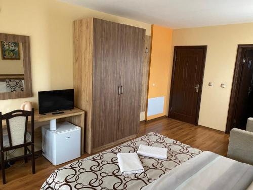 a bedroom with a large bed and a television at Kot Garden Guest House in Sapareva Banya