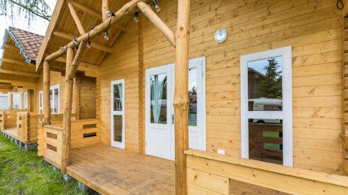 a log cabin with a porch and white doors at Przystań Tło dla Mew in Rydzewo