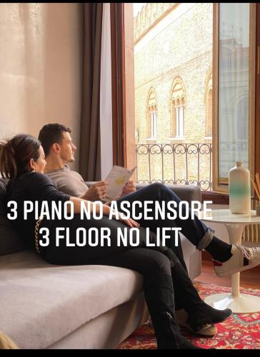 a man and woman sitting on a couch looking out a window at Suite300 by Palazzina300 in Treviso