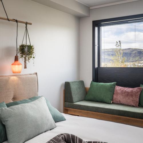 a bedroom with a bed and a couch and a window at The Greenhouse Hotel in Hveragerði