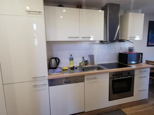 a kitchen with white cabinets and a sink and a microwave at Ferienwohnung und Pension Gürtler in Werdau