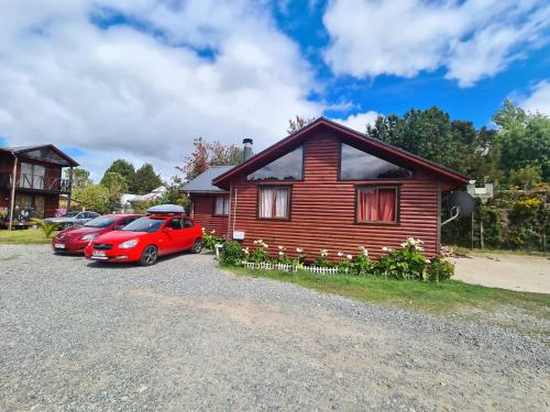 a house with two cars parked in front of it at Cabañas Kompatzki in Ancud