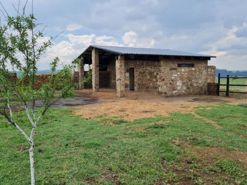 een stenen gebouw met een zwart dak in een veld bij La Vista Farm Stay in Ermelo
