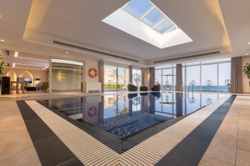 a swimming pool in a hotel lobby with a skylight at Sealine Beach, a Murwab Resort in Mesaieed